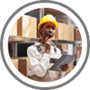 A foreman holds a clip board and looks around a storage shed. 